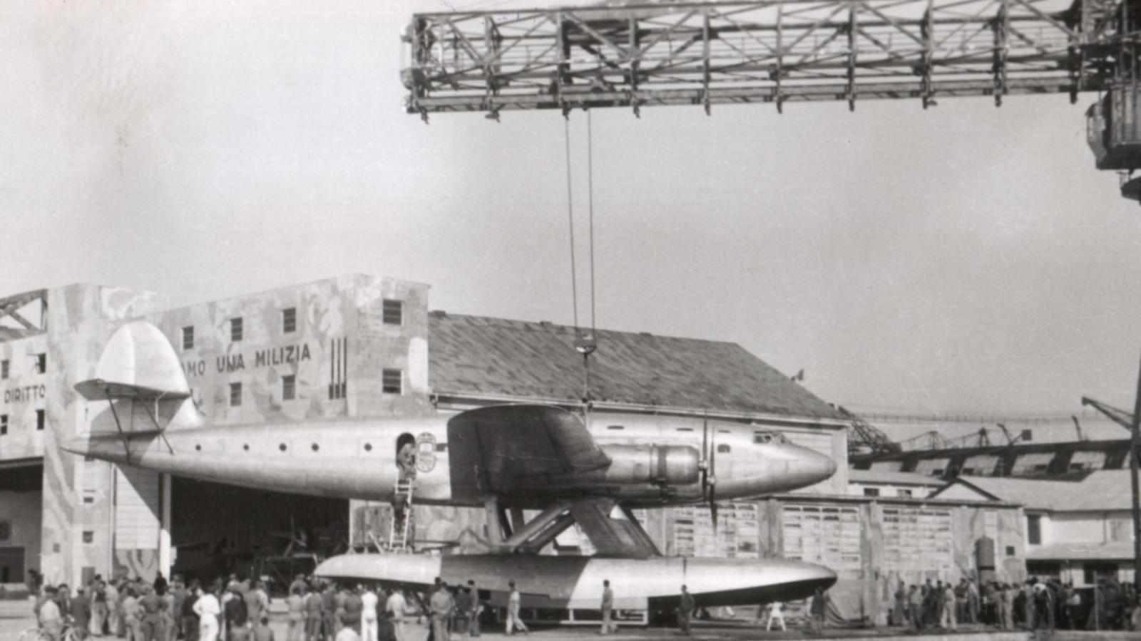 Prototipo velivolo davanti ad area industriale e cantieri navali