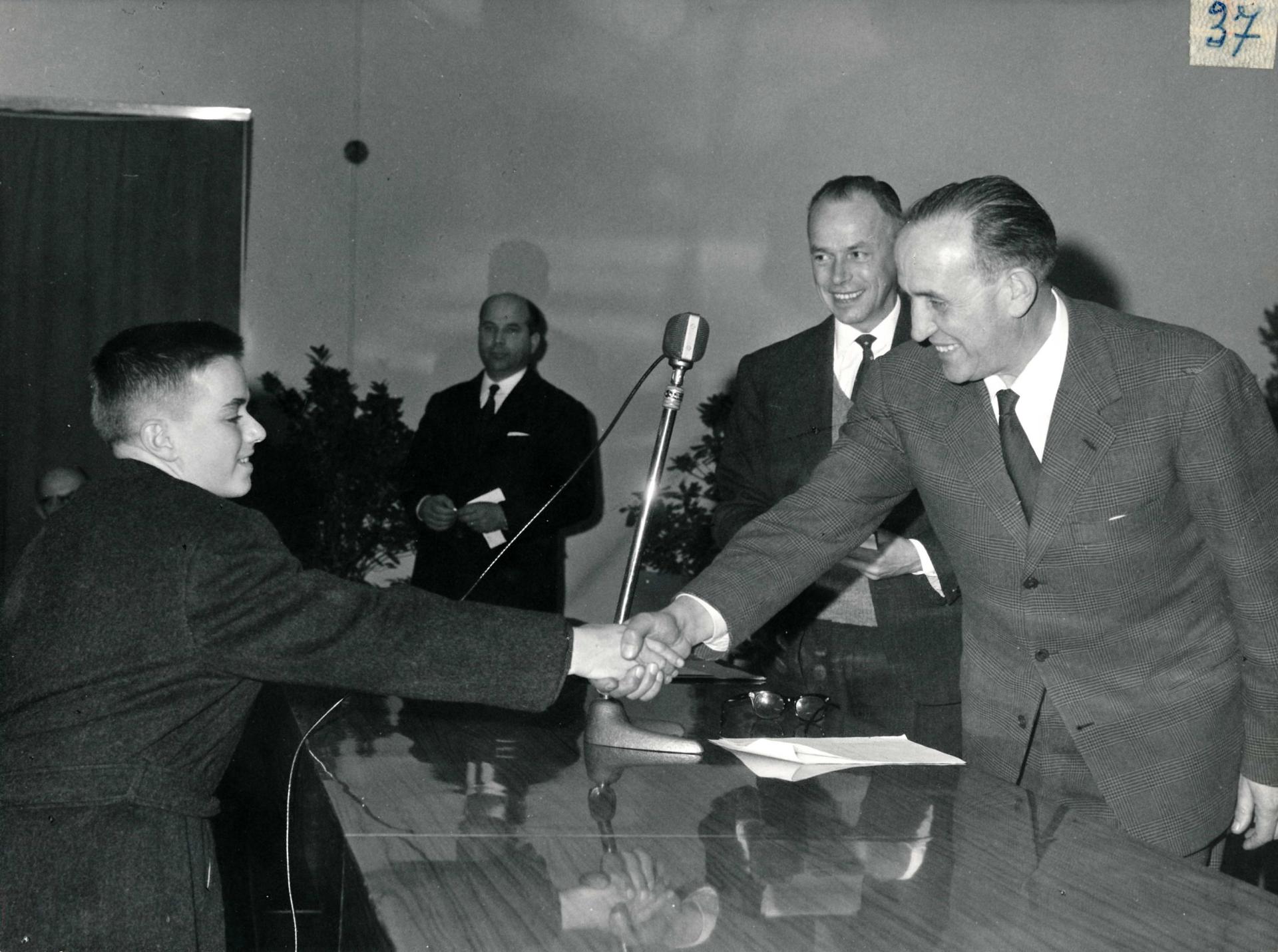 cerimonia premiazione bianco e nero persona anziana giovane stretta di mano